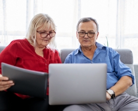 Couple sitting on sofa together, looking at the ADSHG Community platform